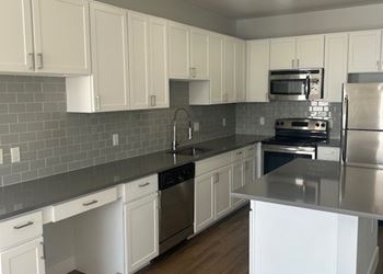 A kitchen with white cabinets and a stainless steel island.